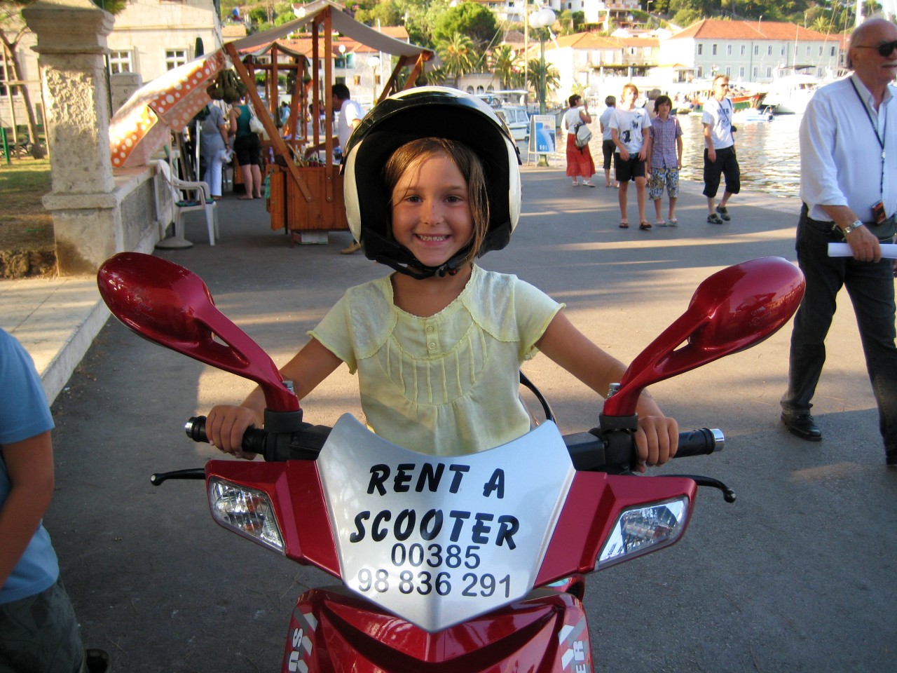Little girl enjoying riding a rented scooter in Vrboska